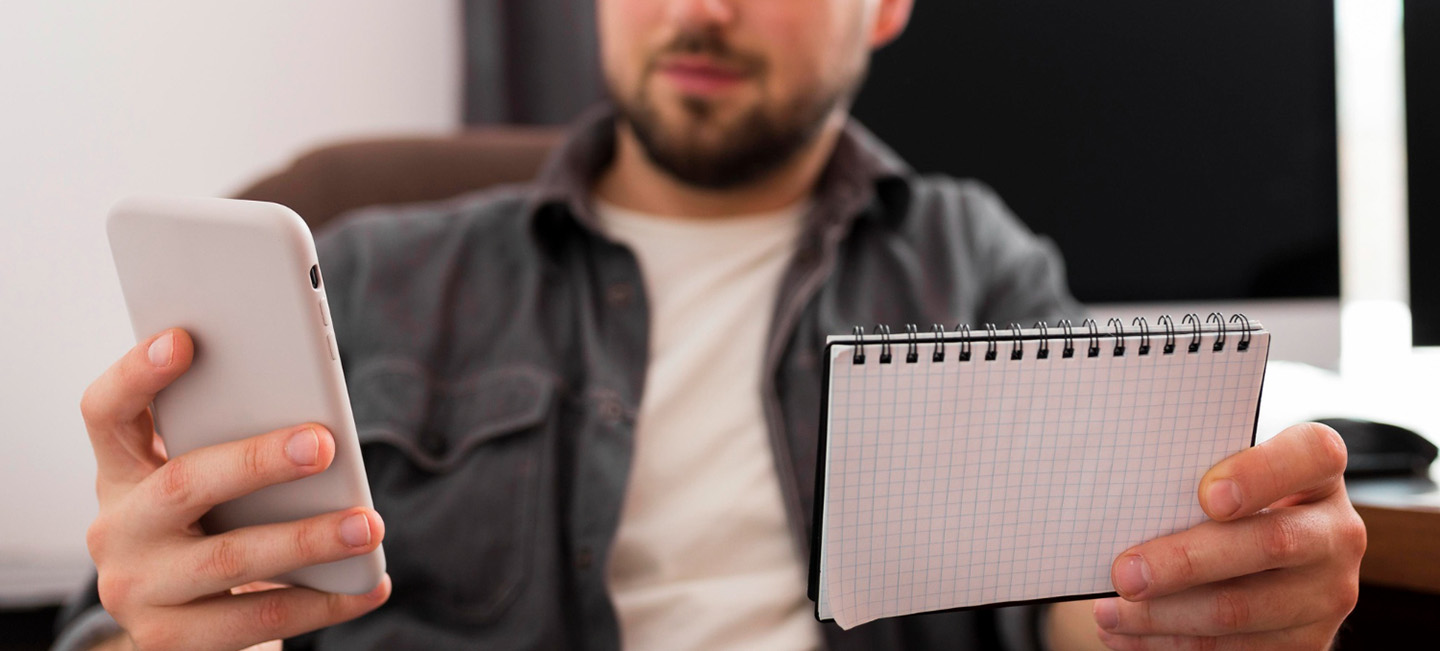 Un hombre consulta un calendario y su teléfono móvil