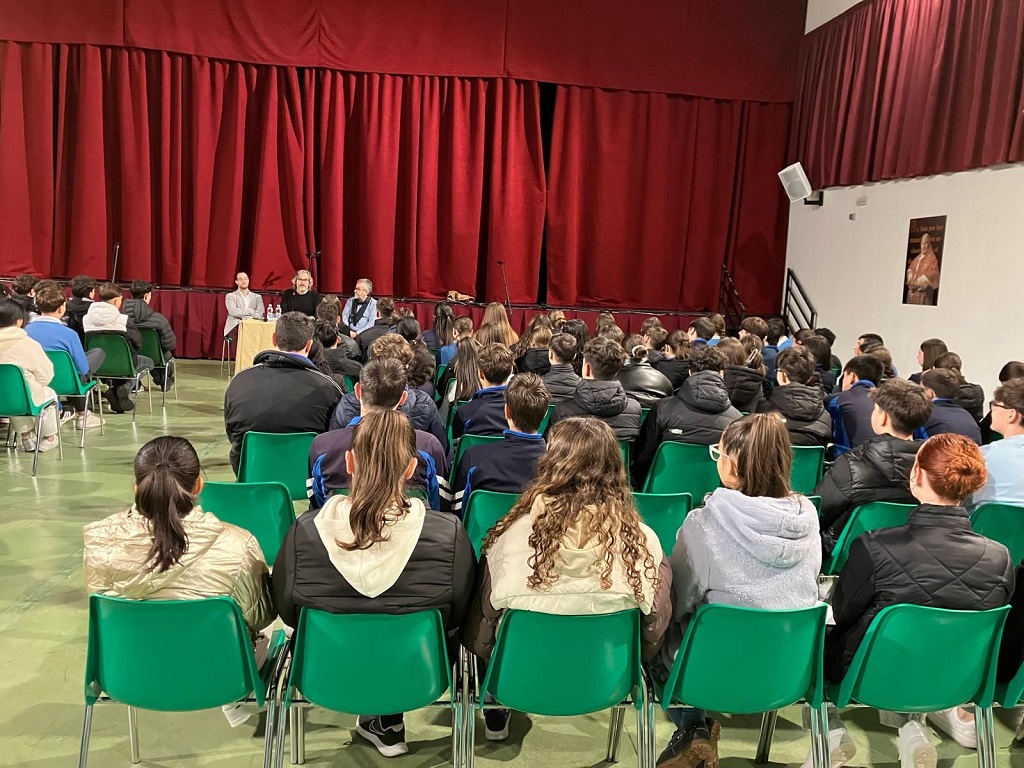 El salón de actos repleto de alumnos que atienden las explicaciones sobre el Día de la Bandera y el significado del símbolo